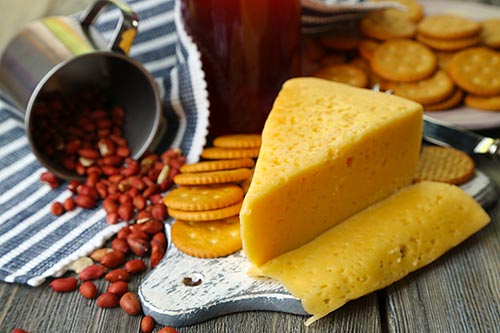 Genießen Sie den Cheddar Käse pur mit Crackern und einem Glas Wein.