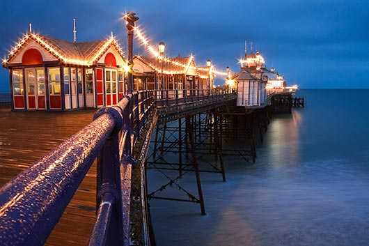 Abends ist der Pier von Eastbourne mit romantischen Lichtern hell erstrahlt.