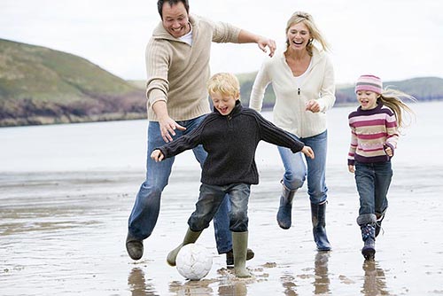 Familie spielt Fußball an Englands Küste